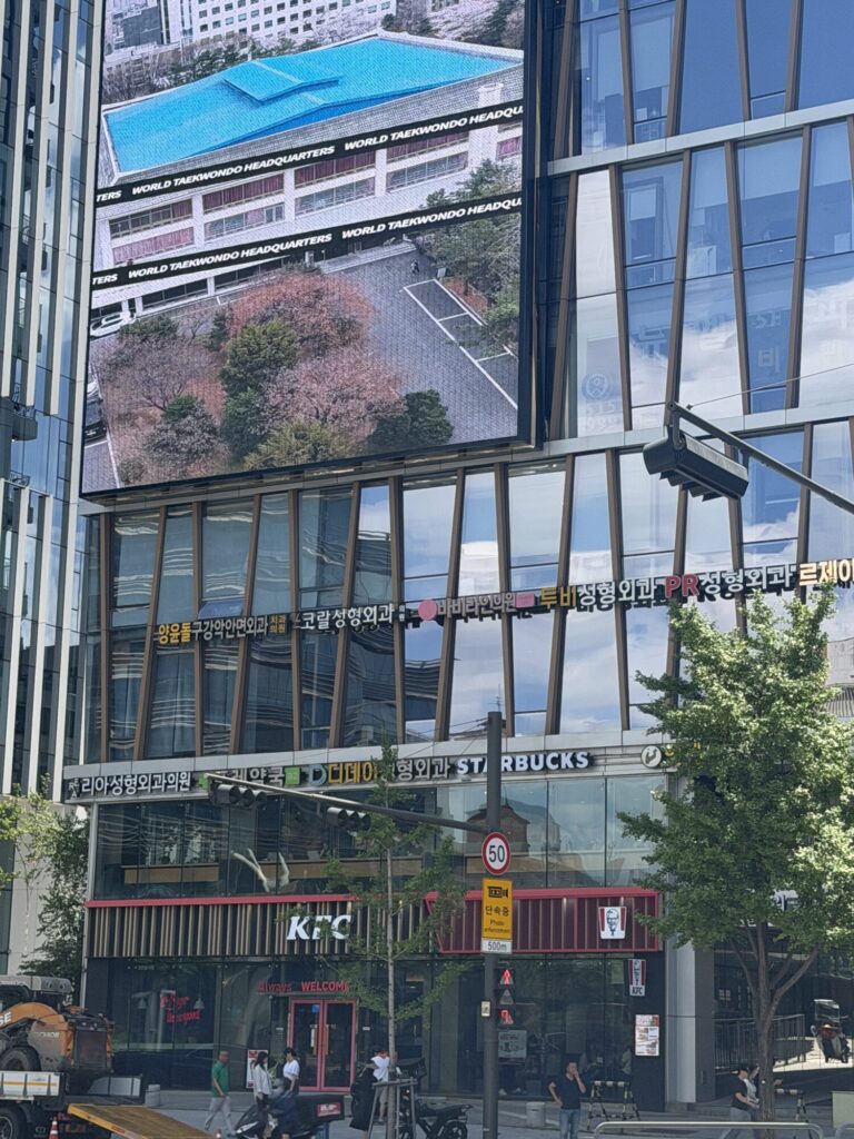 A Seoul street corner with a large video billboard above a Starbucks and a KFC.