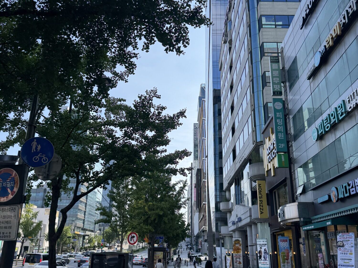 A street in Seoul lined with buildings whose signs advertise clinics and dermatology practices on the upper floors.