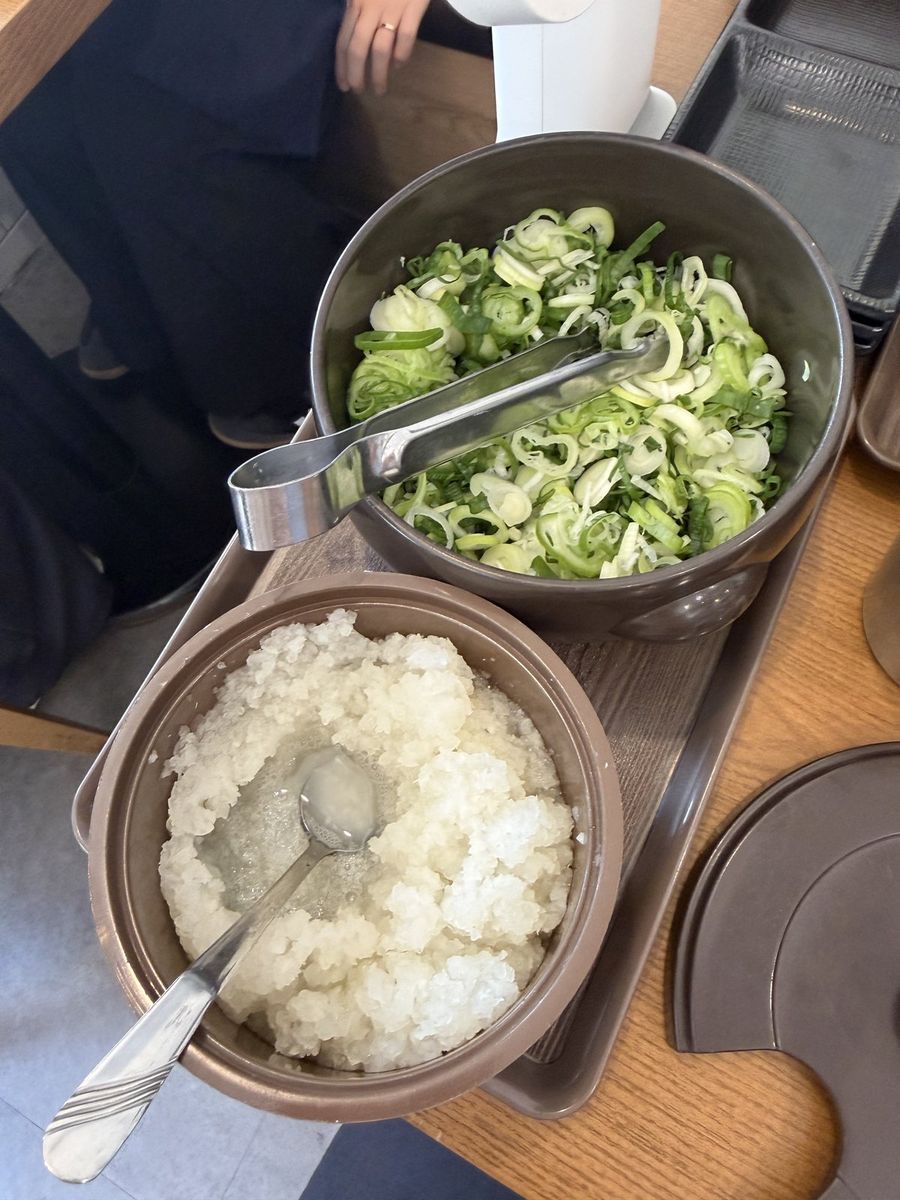 Tubs of chopped scallion and grated white radish kept on the table
