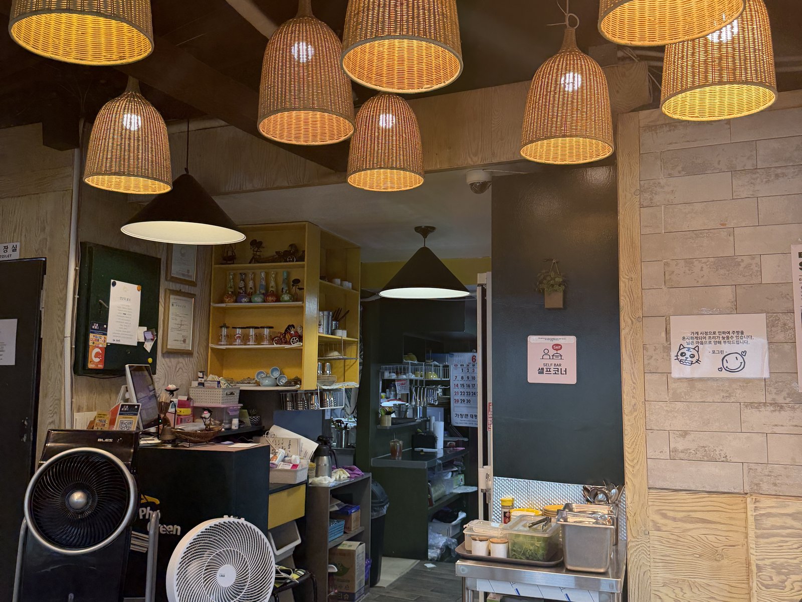 The upstairs dining room: rattan pendant lamps hanging in a cluster, the kitchen counter behind them, and a steel self-service cart by the wall.